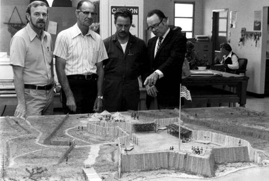 Key persons responsible for research and development of the model of Fort Gadsden now on display at the new museum are shown looking at the finished replica. Standing, left to right, are Patrick Elliot, museum artist; Eddie Nesmith of Apalachicola, retired park supt. At the historic site; Jesse Fairley Jr., museum preparatory; and William Greer of Eastpoint, military miniature figure designer.